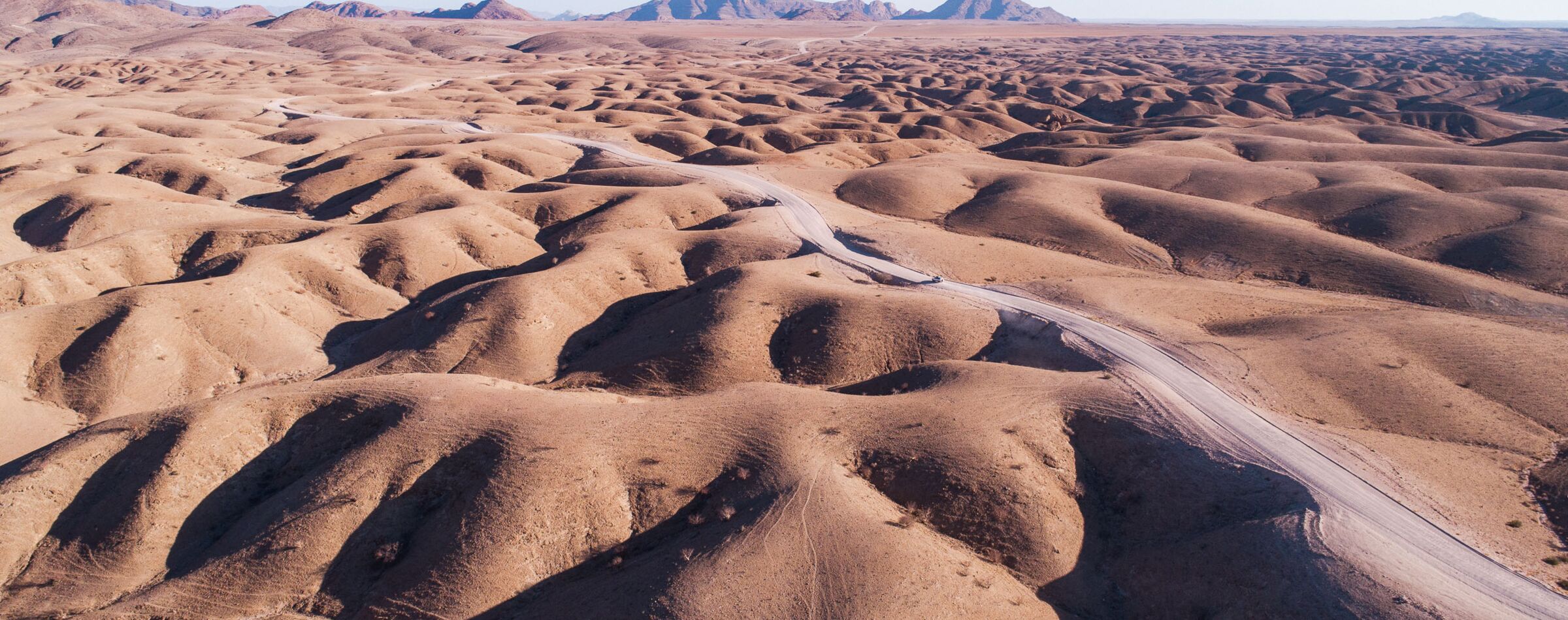 Aerial view of a stunning dune landscape in Namibia with a winding offroad track – a highlight of Gravel Travel adventure tours.